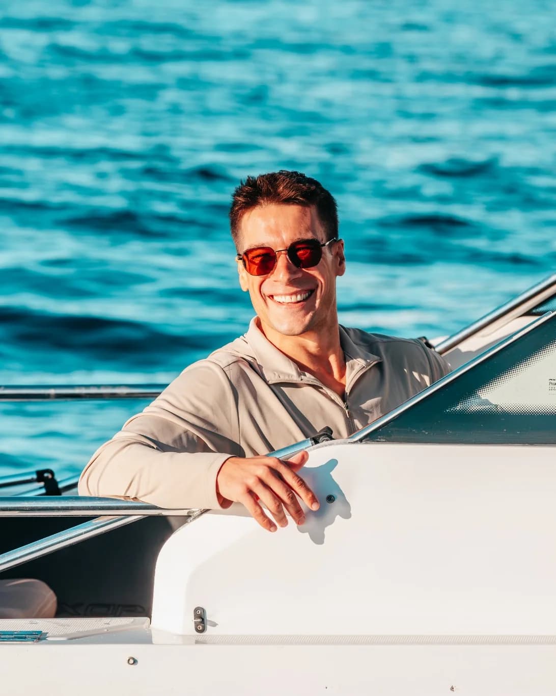 Captain Jeremy smiling at the helm of Sea La Vie, the open water of Moreton Bay behind him