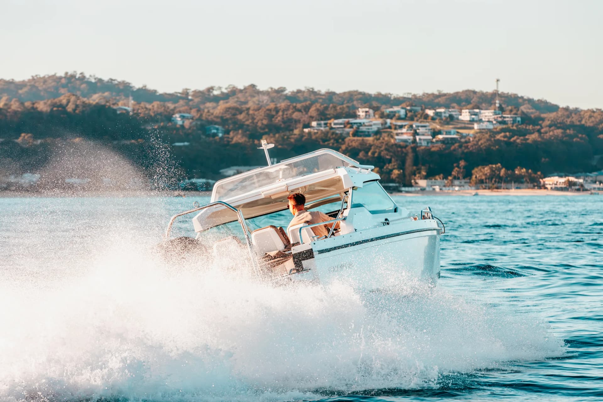 Sea La Vie turning at speed on Moreton Bay, spray lit by late sun