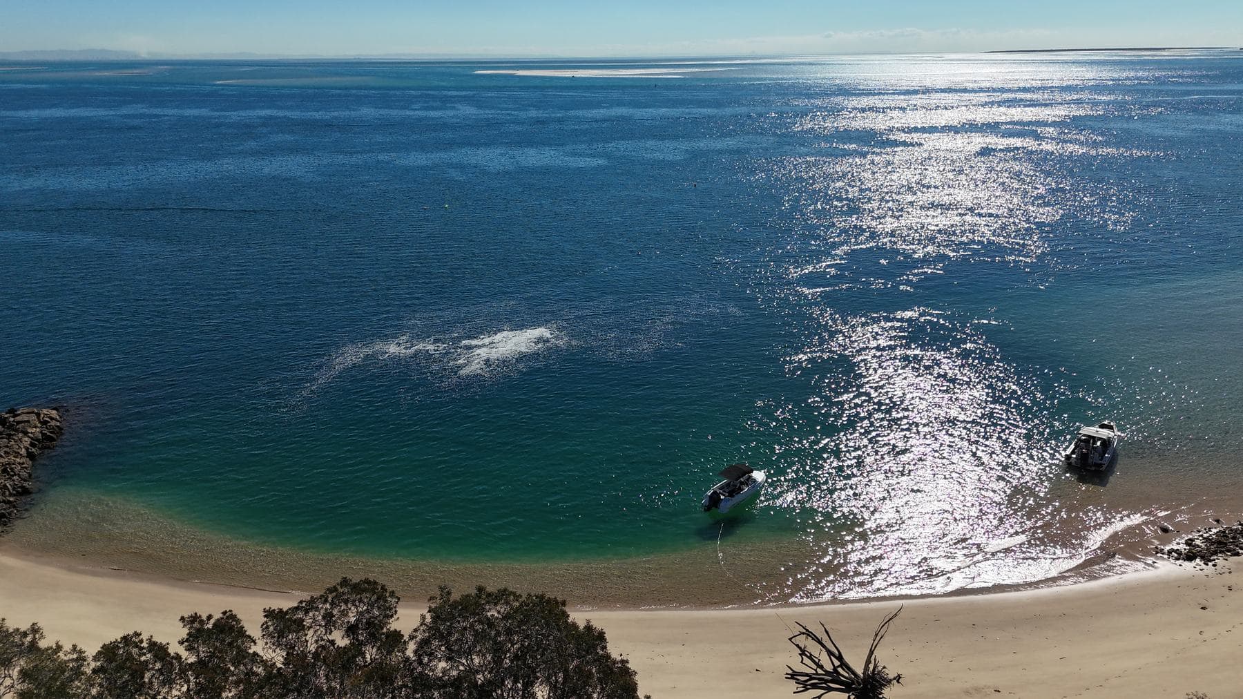 Boats beached in a sparkling cove at Amity with golden sand and clear shallows