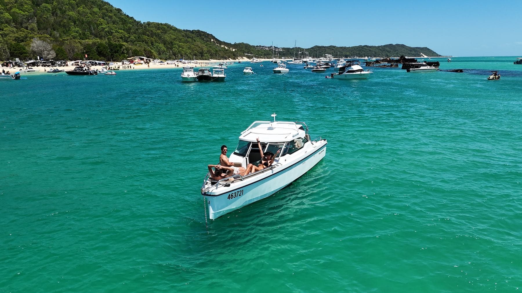 Low aerial of the Axopar with guests on the bow anchored off Tangalooma beach