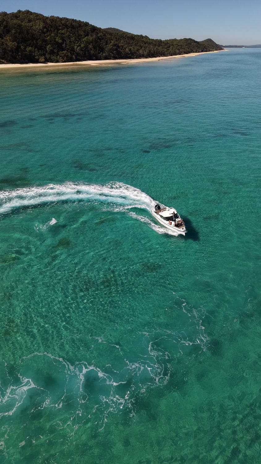 High aerial of the Moreton Island coastline with beach, wreck line and vivid teal shallows