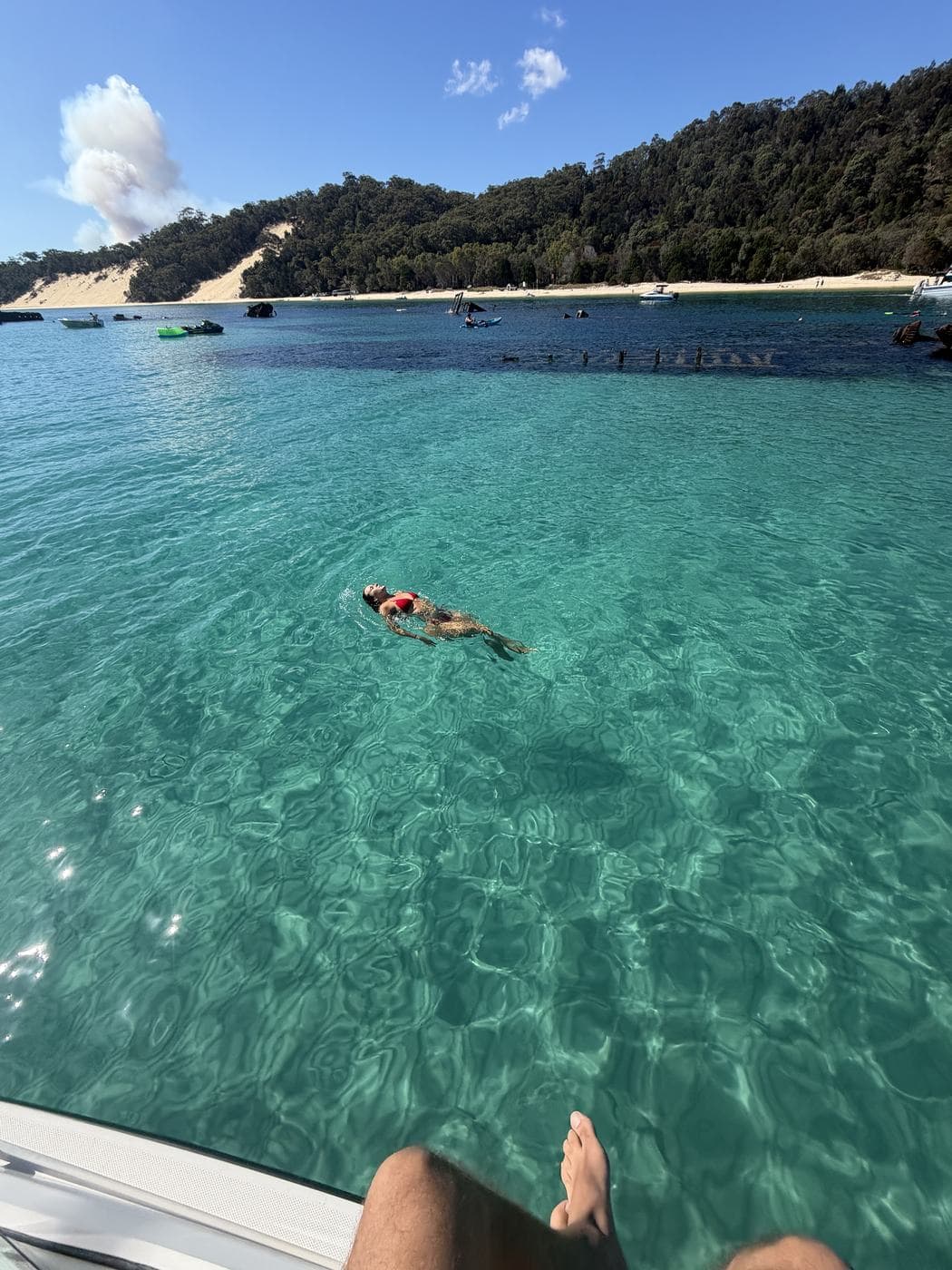 Guest floating on her back in clear aqua water beside the Tangalooma Wrecks