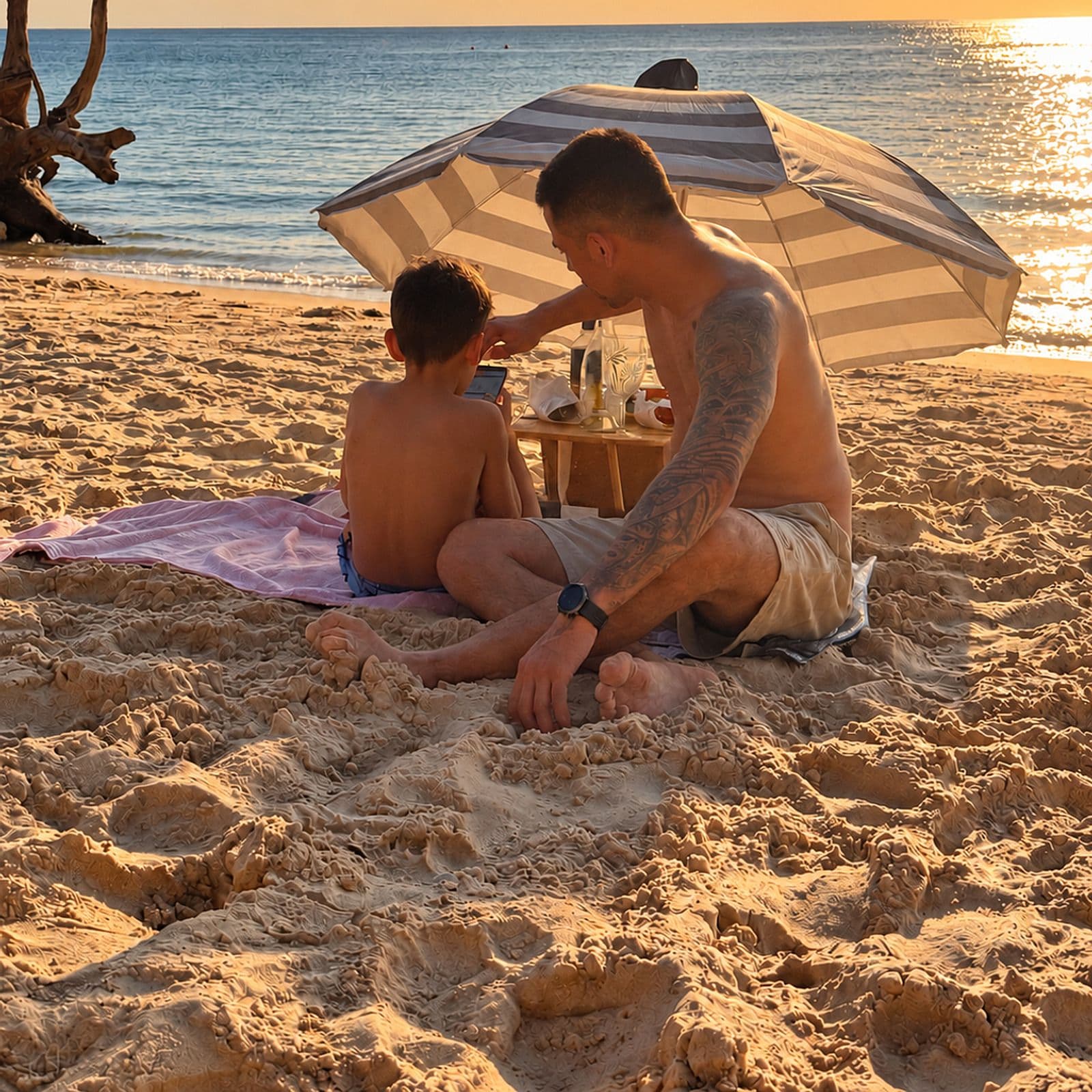 A father and son on the beach at sunset
