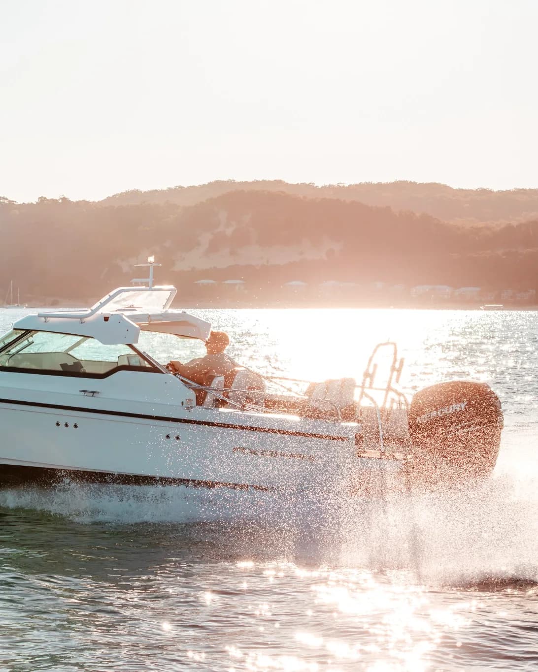The Sea La Vie Axopar 24 running across Moreton Bay in late afternoon light, hills behind