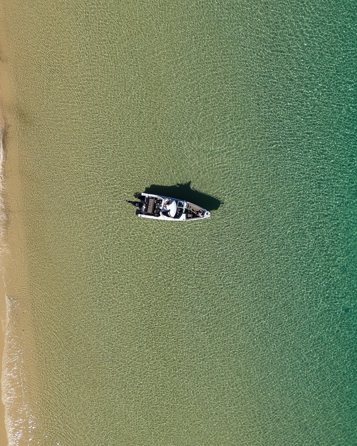 Straight down aerial of the Sea La Vie boat alone on clear shallows beside an empty sandbank