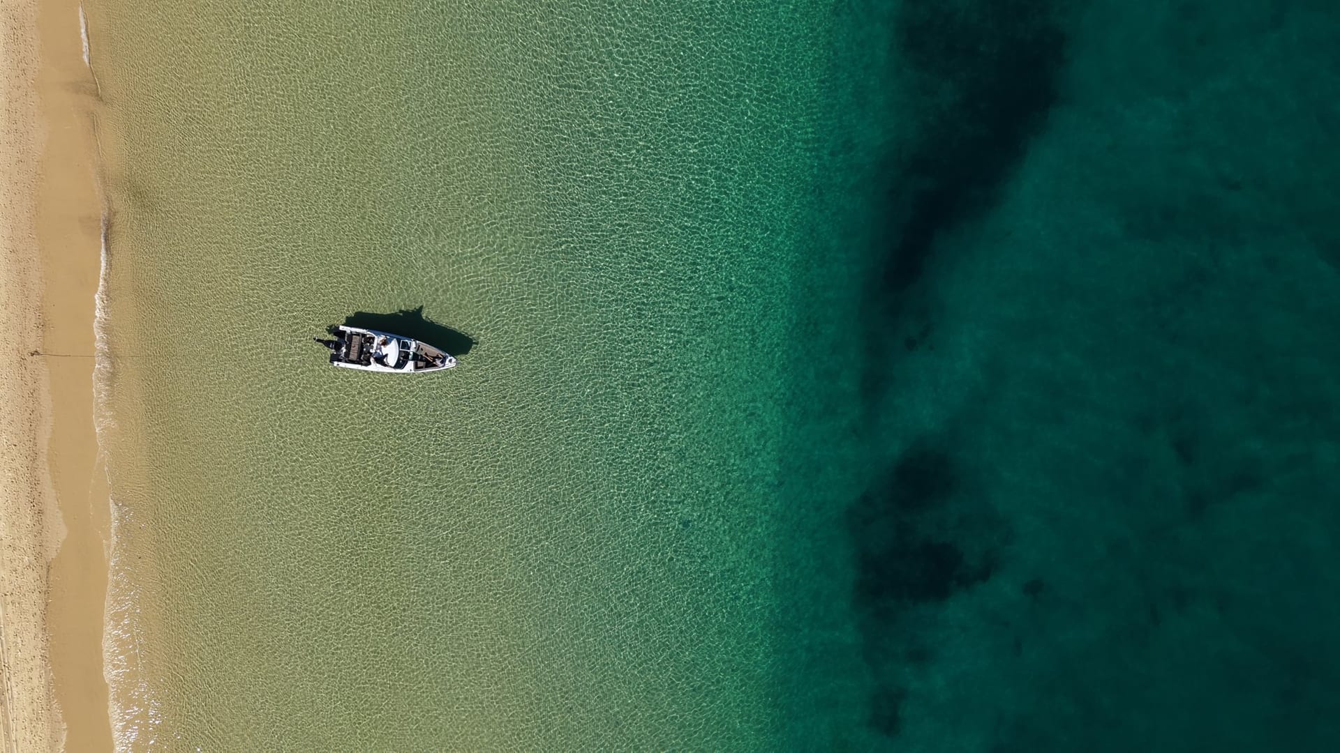 Straight down aerial of the Sea La Vie boat alone on clear shallows beside an empty sandbank