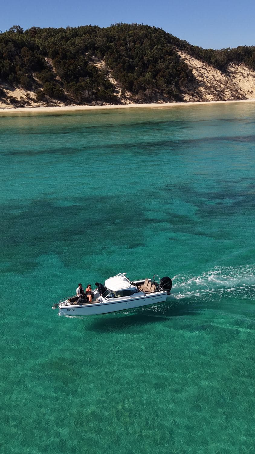 The Sea La Vie Axopar anchored alone on a glassy emerald reef flat off Peel Island