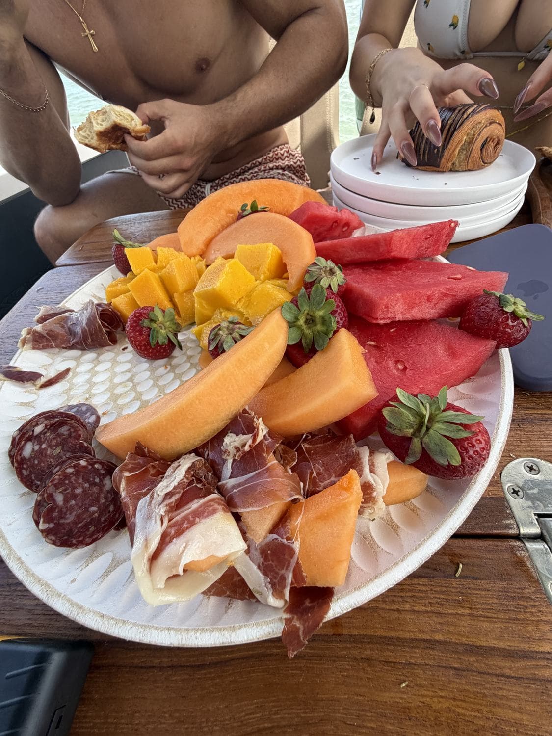 Overhead of a grazing platter of cheeses, charcuterie and fruit served on board