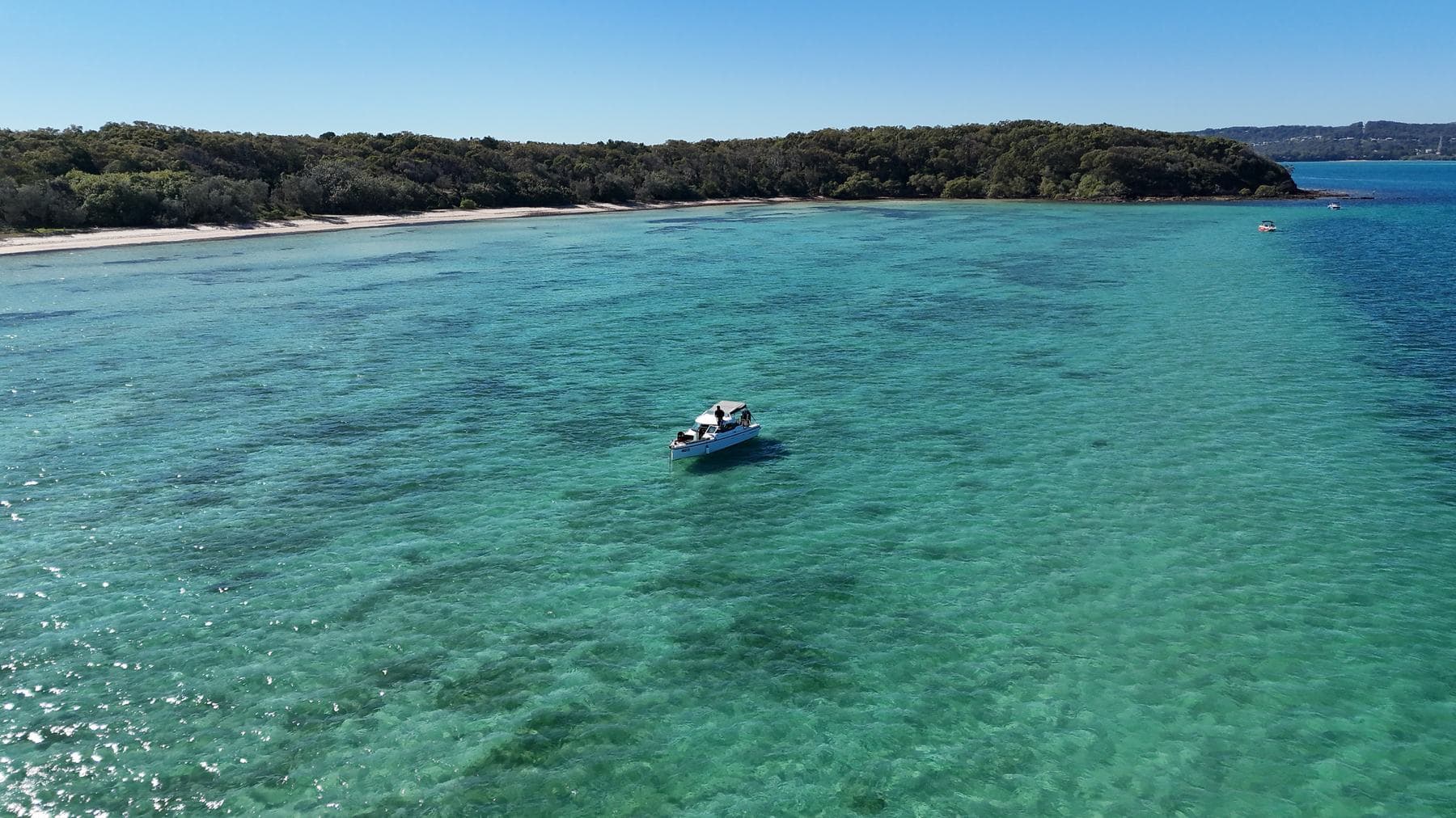 The Sea La Vie Axopar anchored alone on a glassy emerald reef flat off Peel Island