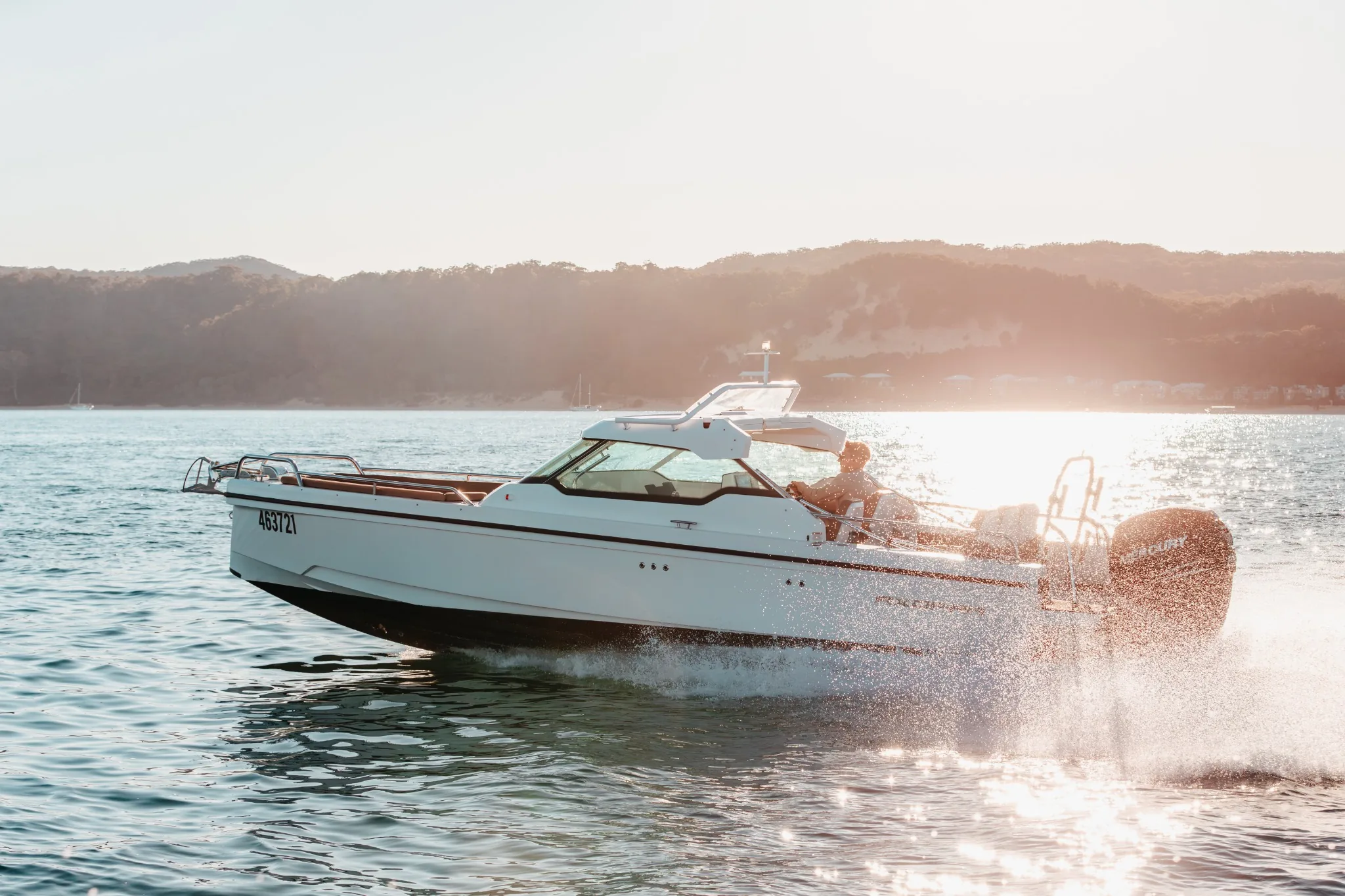 The Sea La Vie Axopar 24 running across Moreton Bay in late afternoon light, hills behind